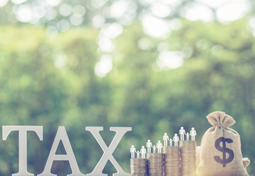 "TAX" wooden blocks placed on IRS forms 1040, W-9, and 1120 with a calculator.